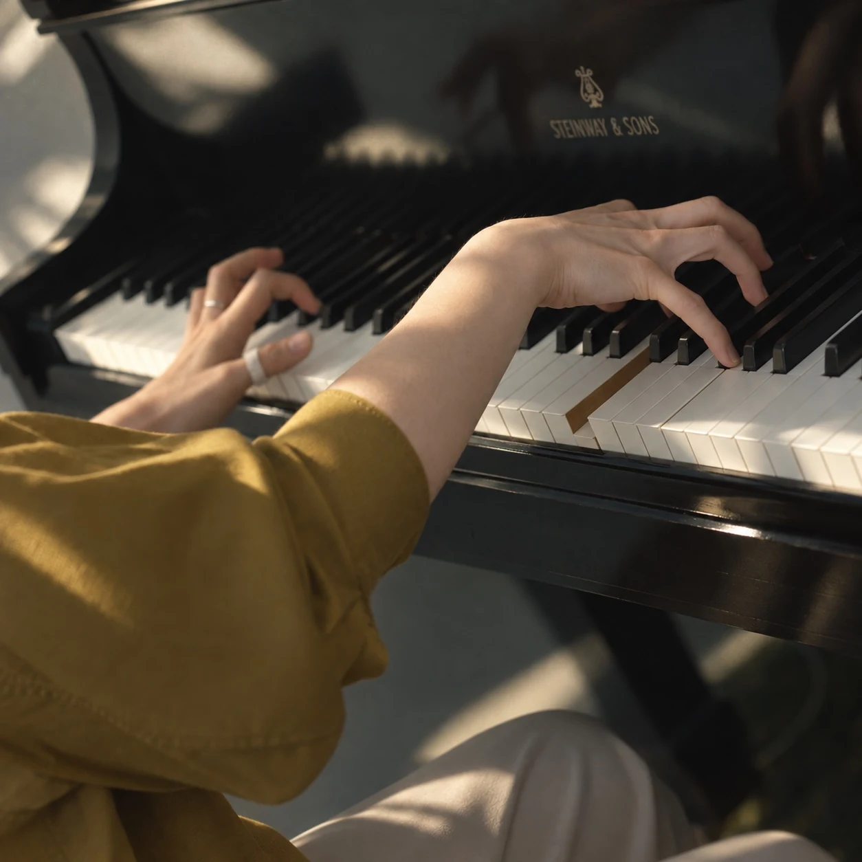 The Margins — hands playing a piano in warm afternoon light