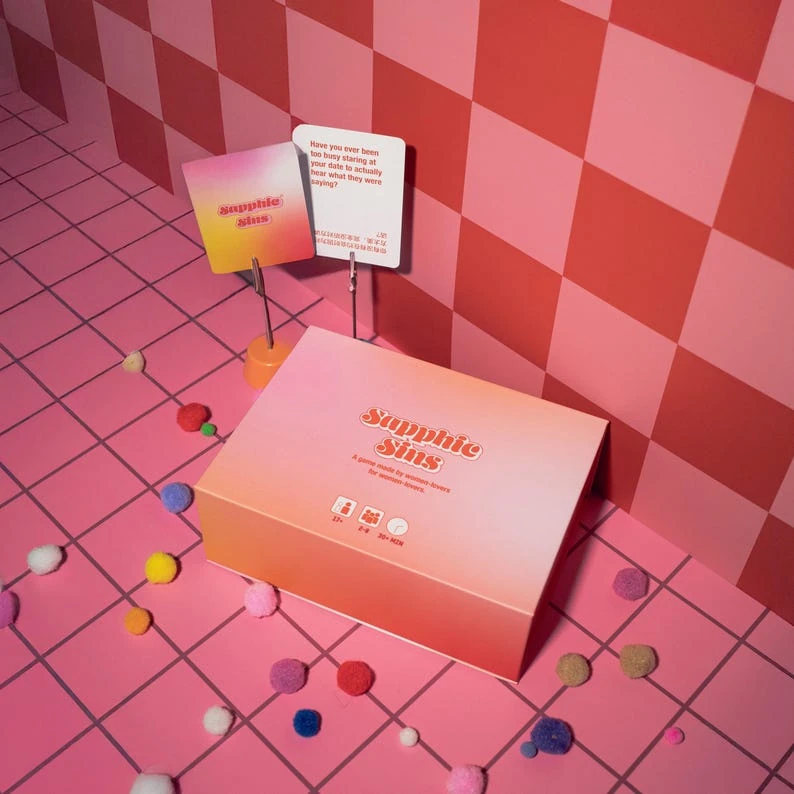 Sapphic Sins game box and cards on a pink checkerboard set